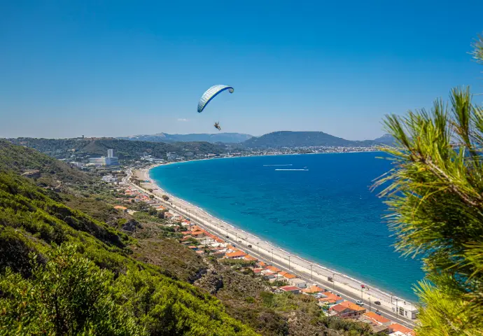 a paraglider flying over a beach next to the ocean