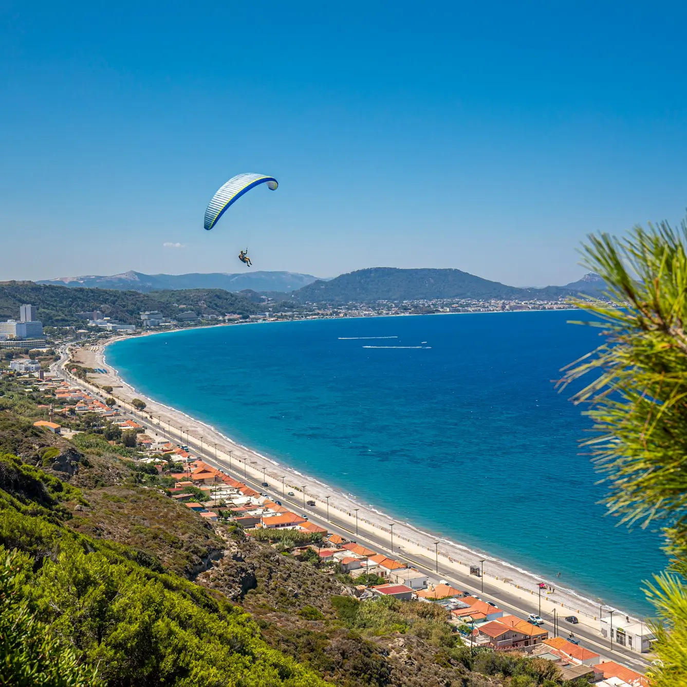 a paraglider flying over a beach next to the ocean