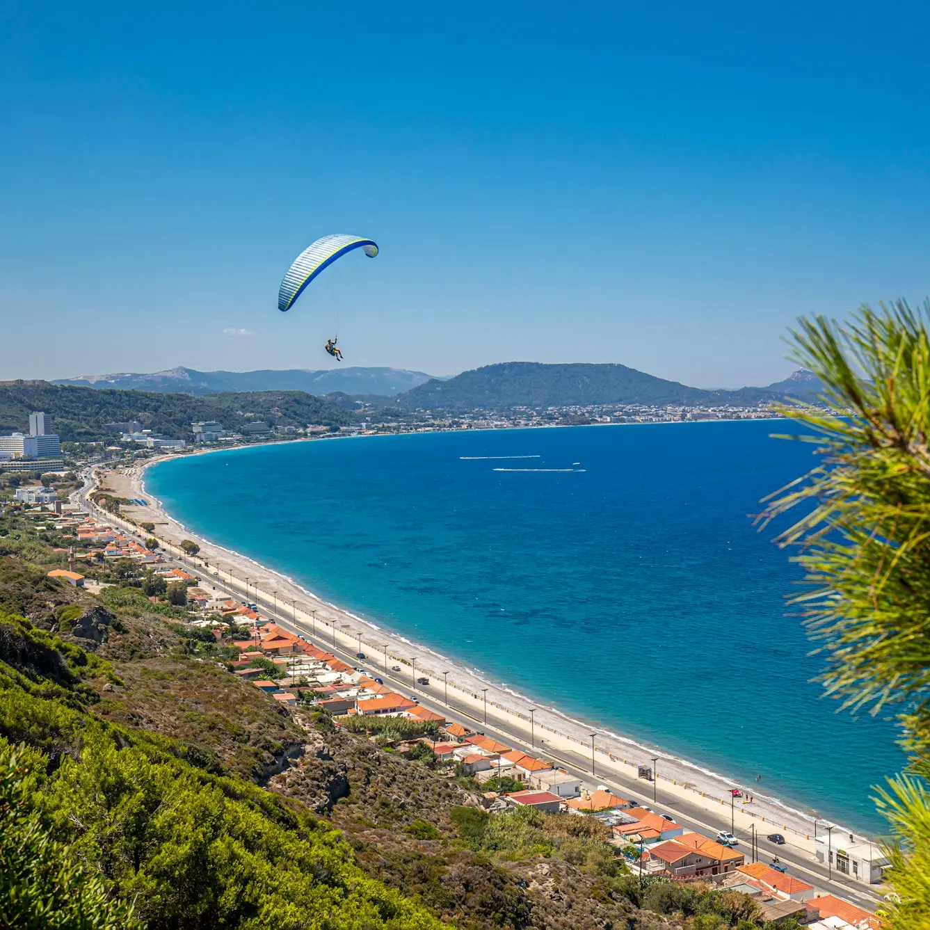 a paraglider flying over a beach next to the ocean