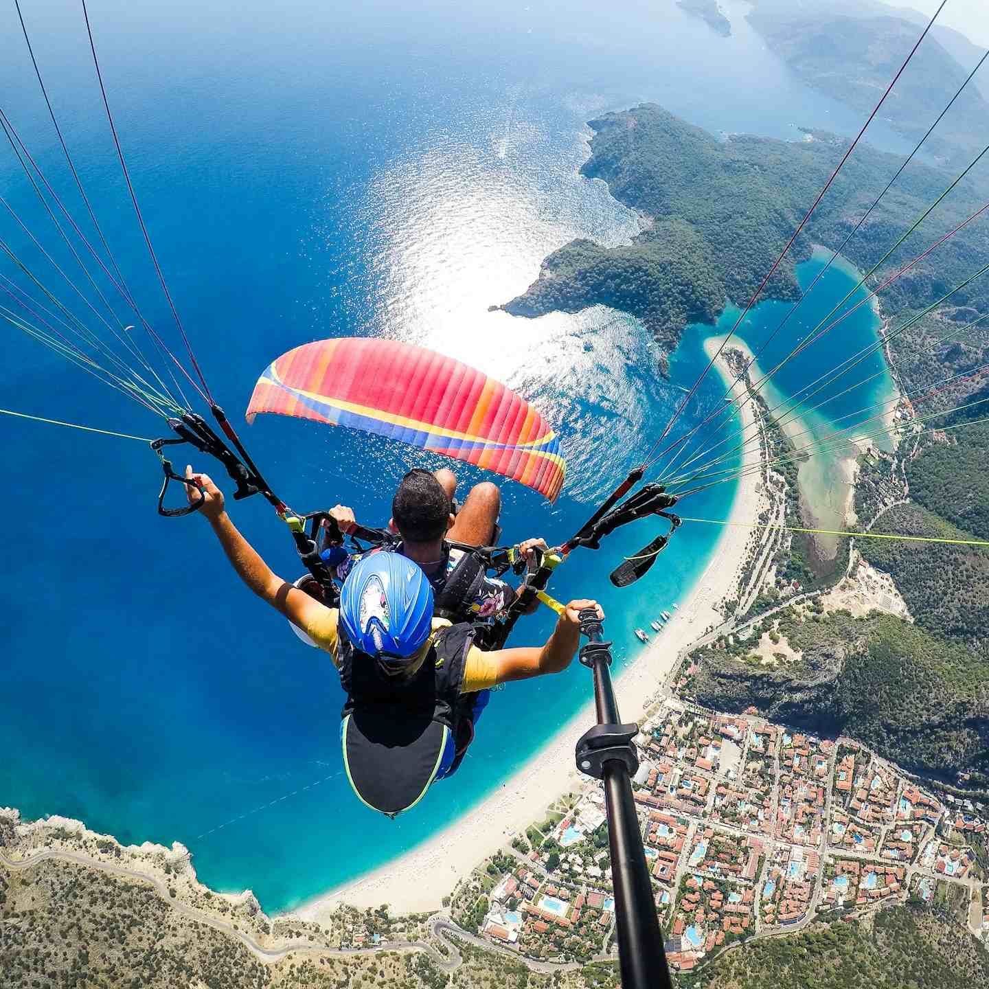man in blue and black jacket riding on blue and white parachute