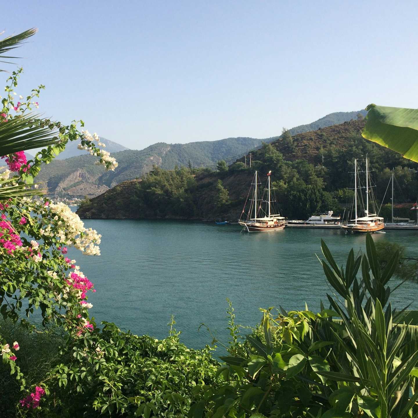 white boat on body of water near mountain during daytime